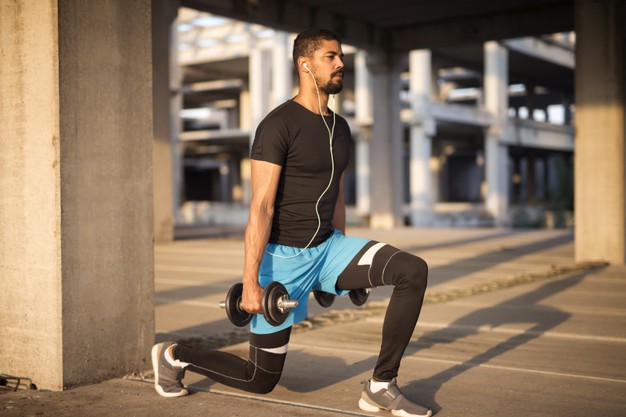 Sportsman listening to music and training with weights