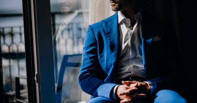 thoughtful-man-blue-suit-sits-windowsill