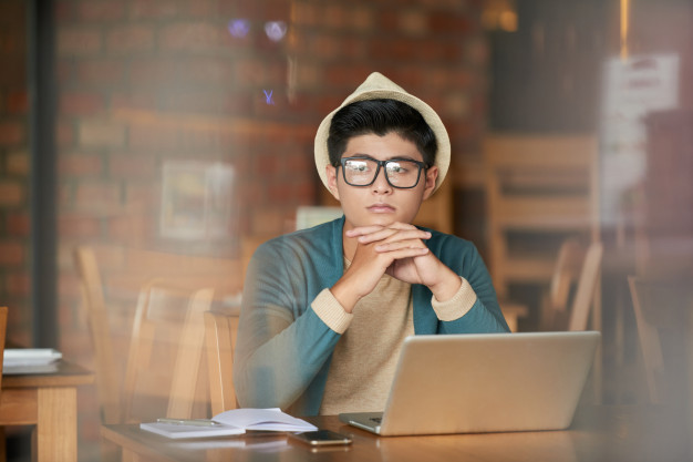 young-asian-hipster-man-sitting-cafe-with-laptop-gazing-away