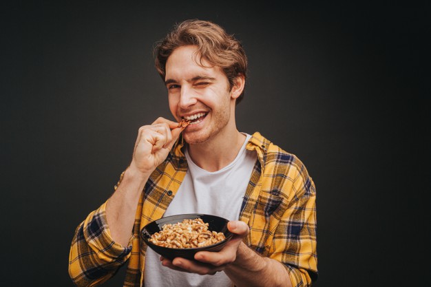 young-blond-man-yellow-shirt-is-eating-peeled-walnut