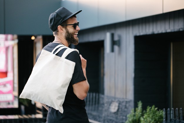  man holding white textile eco bag against urban city background