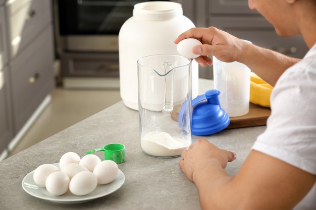 Young sporty man preparing protein shake at table