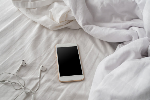 Blank screen smart phone on white bed