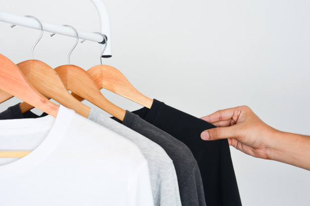 Man's hand choosing black color t-shirt from collection of black