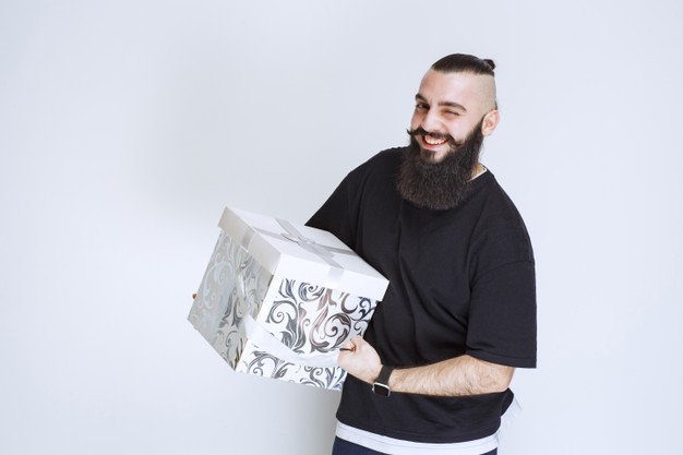 Man with beard holding a white blue gift box smiling and feeling happy