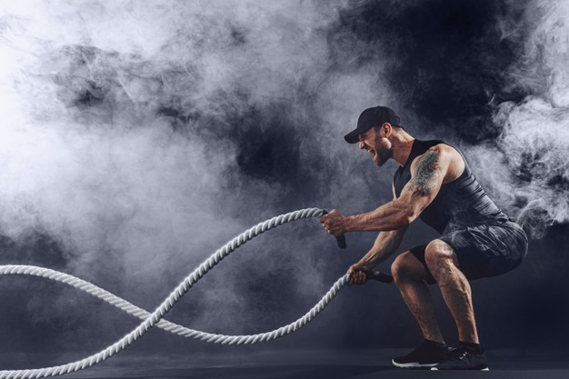 Muscular tattooed bearded male exercising