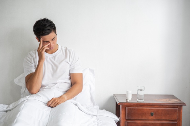 The sick man sat on the bed, touching her head with his hand