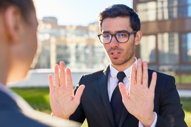male shows stop gesture has displeased facial expression denies