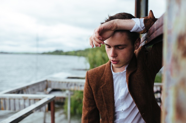 The young man posing on a pier with sea