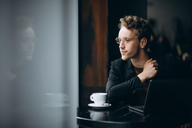 handsome-man-working-computer-cafe-drinking-coffee