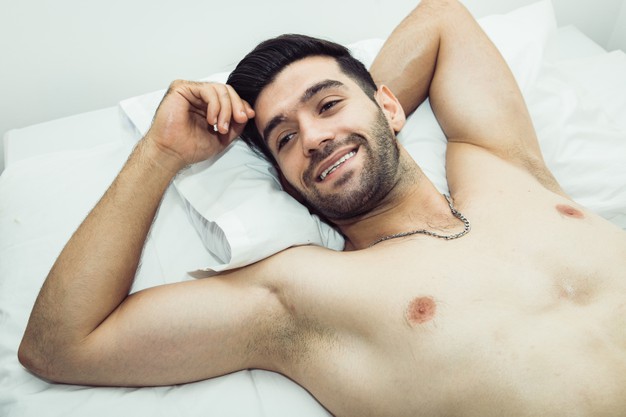 Handsome shirtless man laying on bed and have positive thinking with looking away.