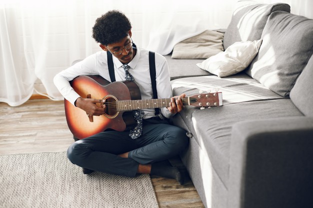 man in tights sitting in the living room. musician playing the guitar