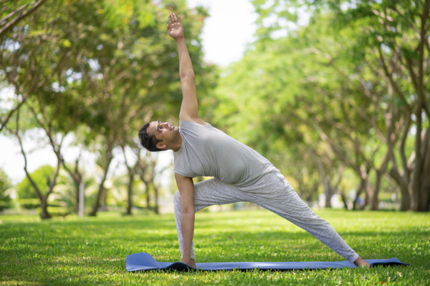 man doing yoga asanas in city park. young citizen exercising outside