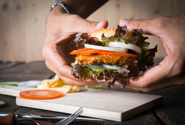 Man holds burger with hands and potato chip