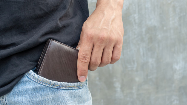 Men hold a brown wallet from a jeans pocket