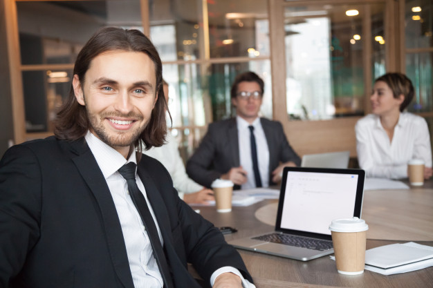 Smiling businessman manager in suit looking at camera at meeting 