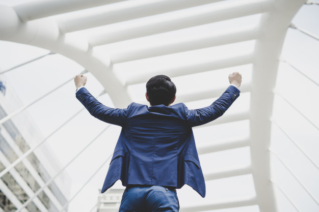 successfully-young-businessman-keeping-arms-raised-expressing-positivity-while-standing-outdoors