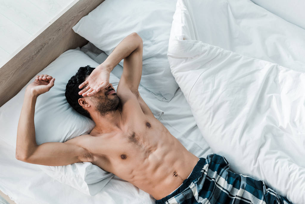 handsome shirtless bearded man sleeping in bed 