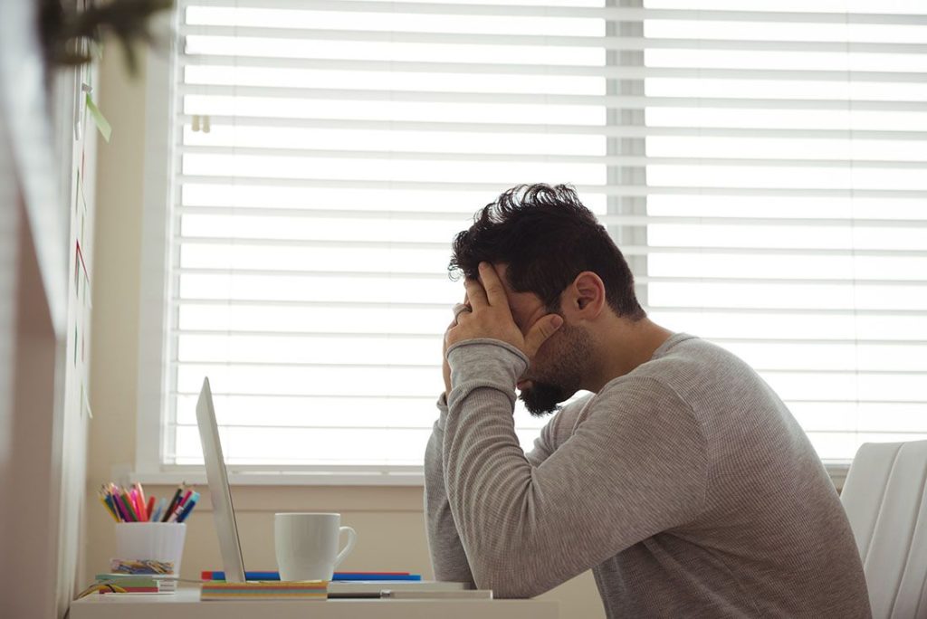 Stressed man sitting with hands on head 