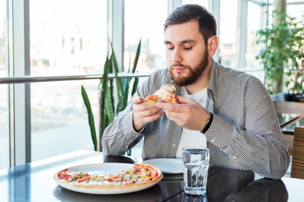 Hungry caucasian man eating italian pizza in pizzeria. delicious pizza in cafe