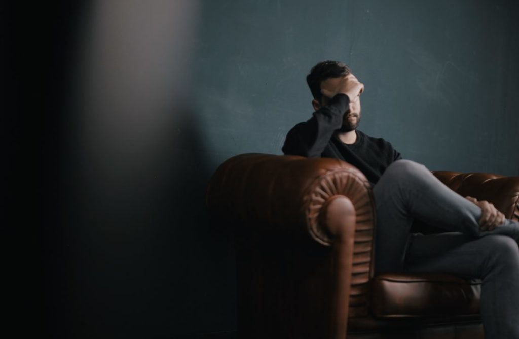 man in black shirt with headache touching head in apartment