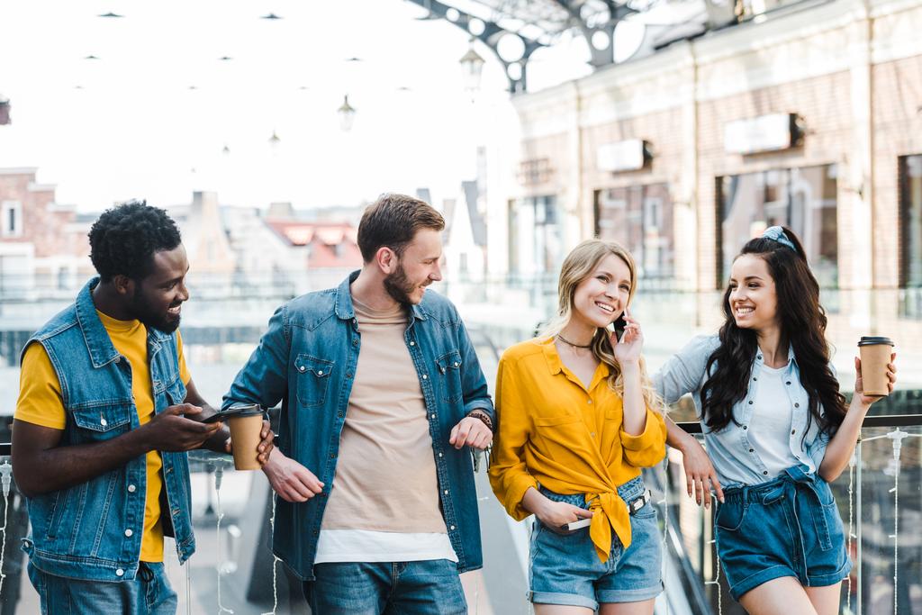 Cheerful woman talking on smartphone near multicultural friends