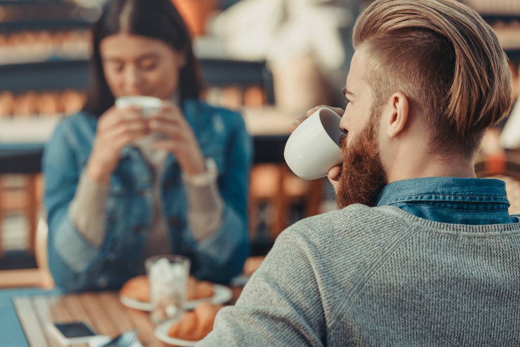 Young couple drinking coffee in cafe outdoors