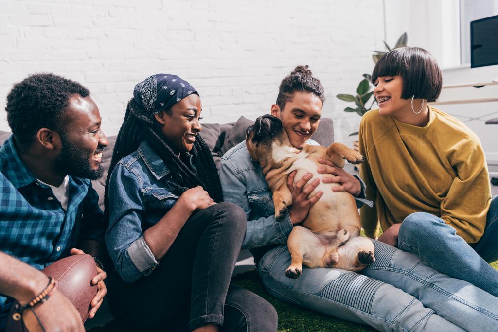 Group of smiling young multicultural friends with french bulldog