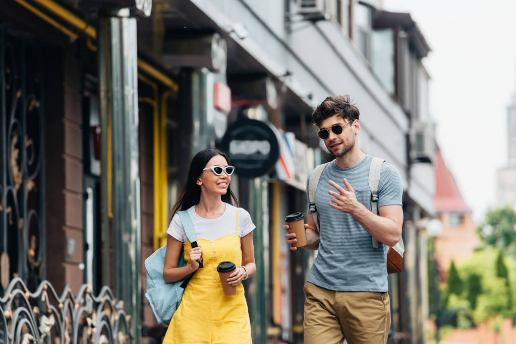 Handsome man and asian woman talking and holding paper cups