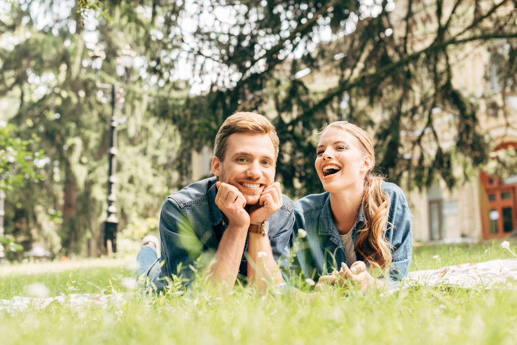 Laughing young couple lying on grass at park