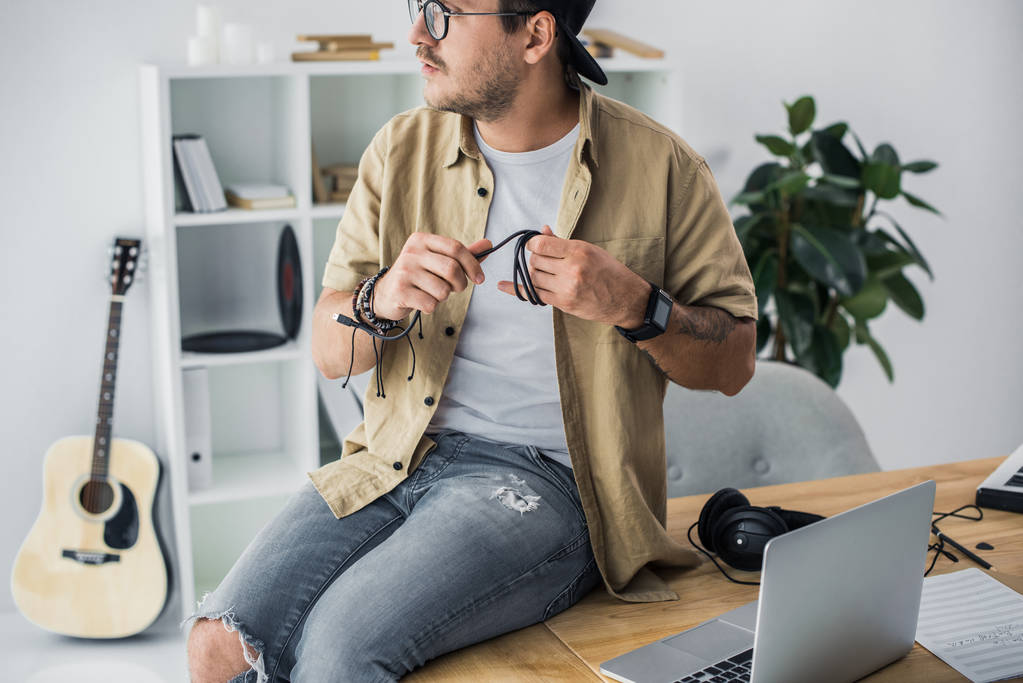 Young handsome man sitting on worktable and looking away 