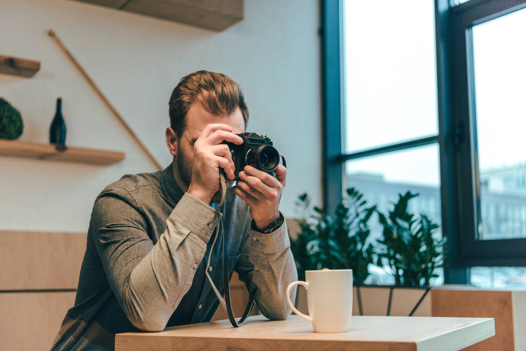 man taking picture on photo camera in cafe