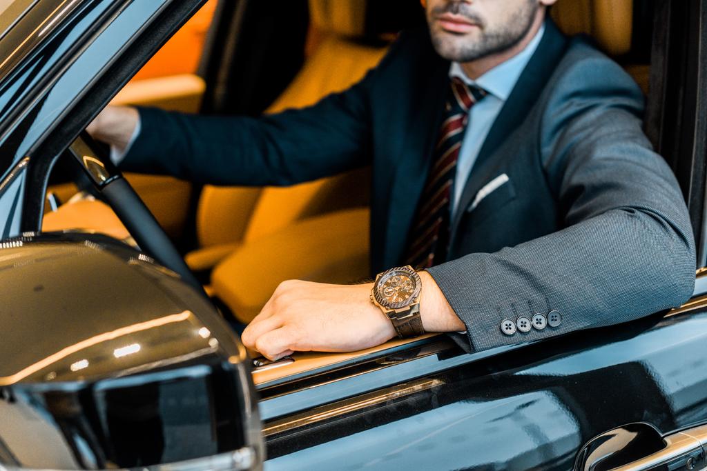 businessman with luxury watch sitting in automobile