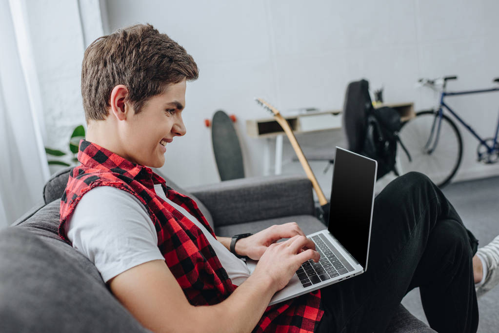teenager typing on laptop while sitting on sofa 