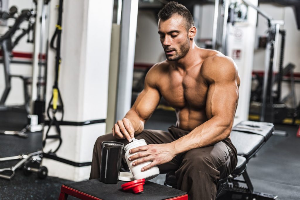 man prepares a protein shake or uses a sports food supplement in the gym