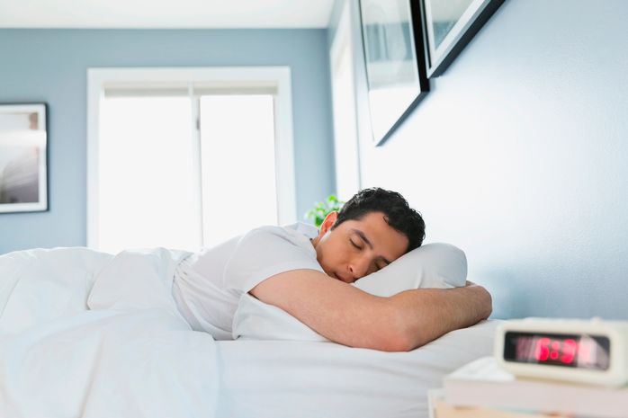 man sleeping lying face down on bed