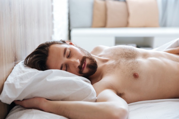 Attractive bearded young man sleeping in bed