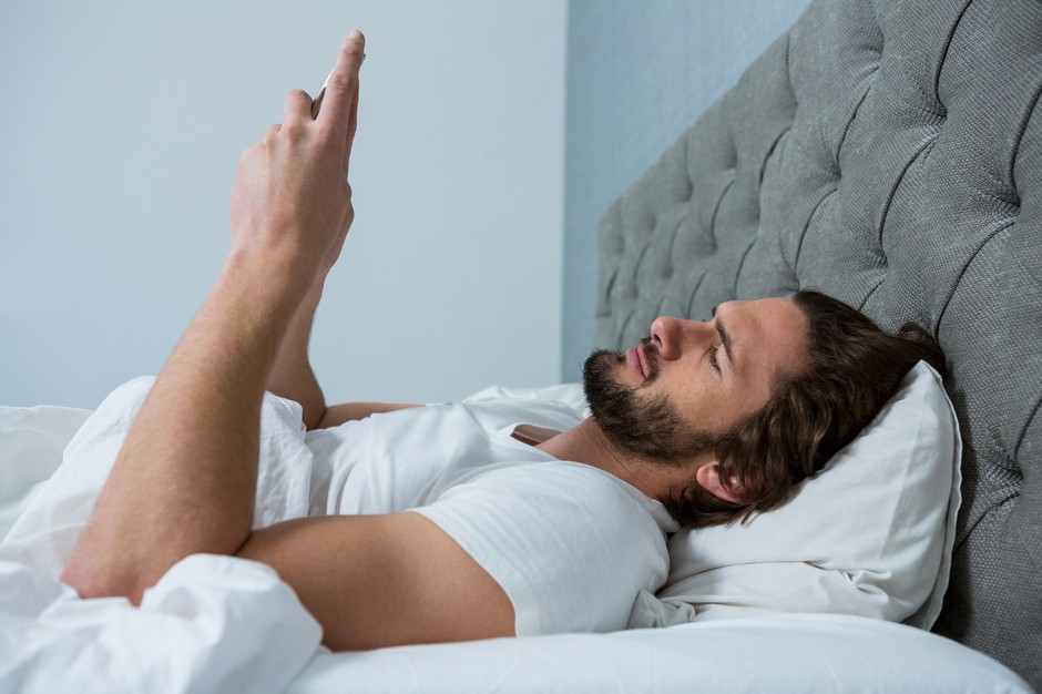 Man using mobile phone in bedroom 