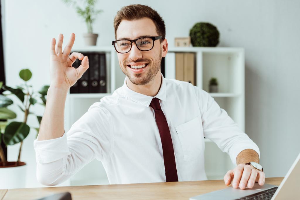 handsome businessman with laptop showing ok sign