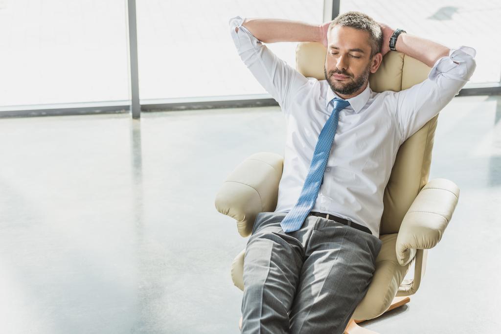 handsome businessman relaxing on luxury armchair at modern office 