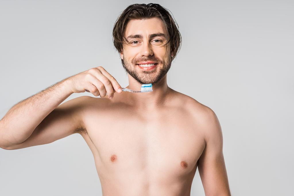  smiling shirtless man with tooth brush isolated on grey