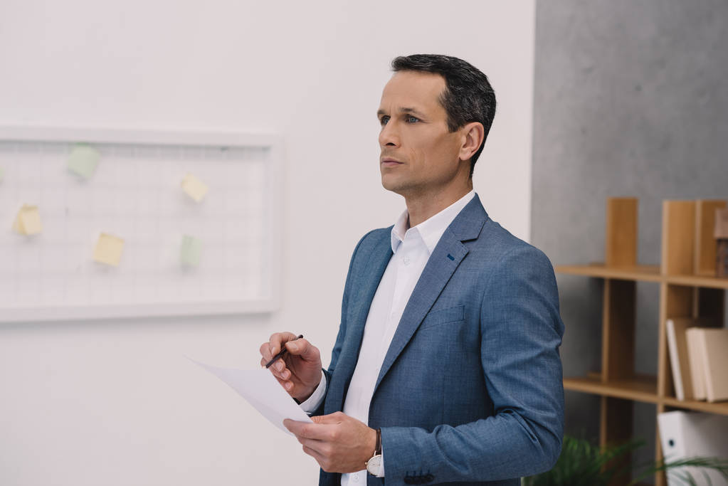 man with business paper looking away at office