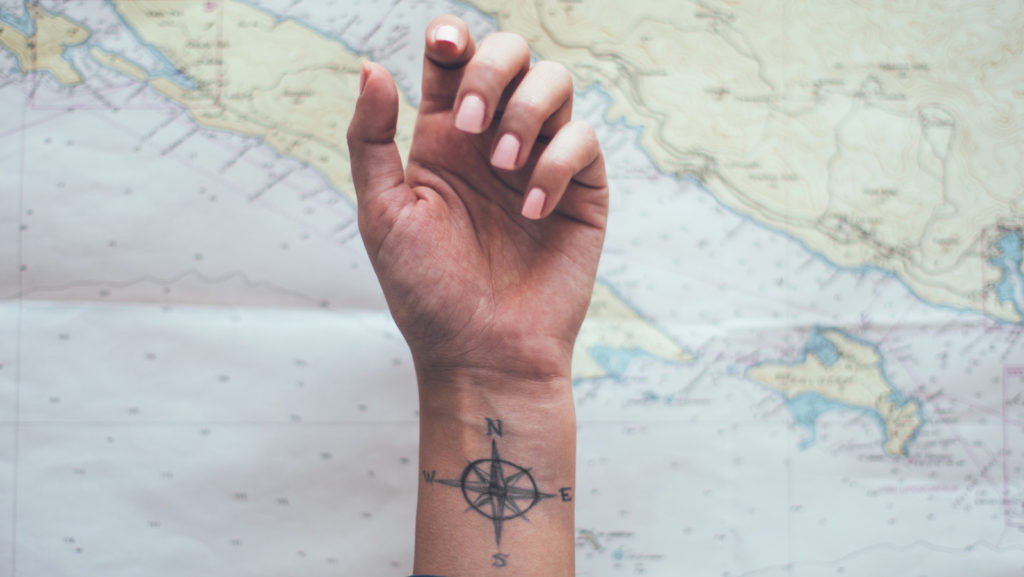 Compass,Tattoo,On,Sailor,Ankle,With,Nautical,Chart,In,Background.
