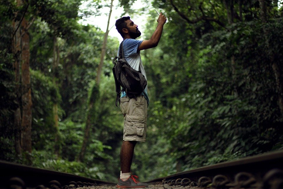 Man In Jungle and taking a picture with smart phone