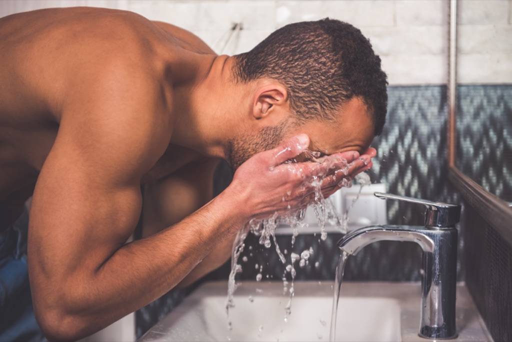 Young man spraying water on his face