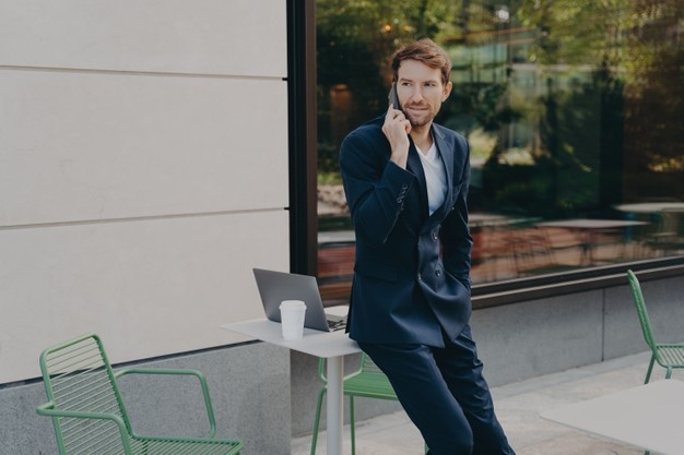 Young stubbly man entrepreneur in formal wear talking phone