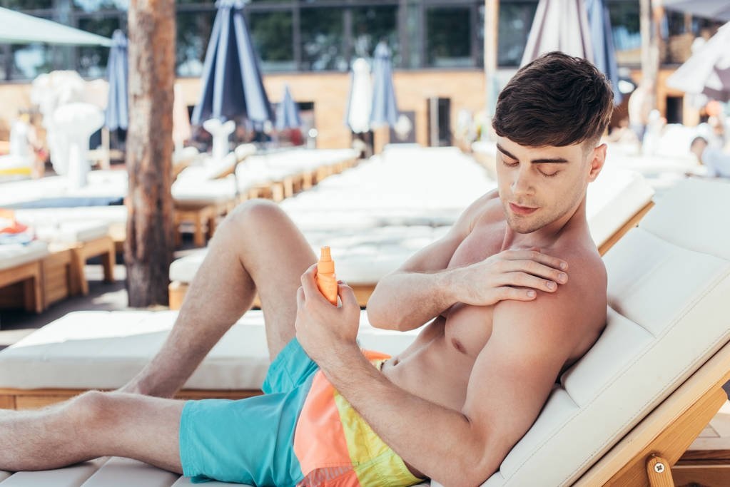Handsome Young Man Applying Sunscreen Lotion