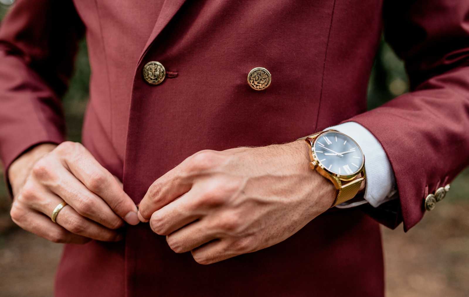  man wearing a suit and golden watch buttoning his jacket