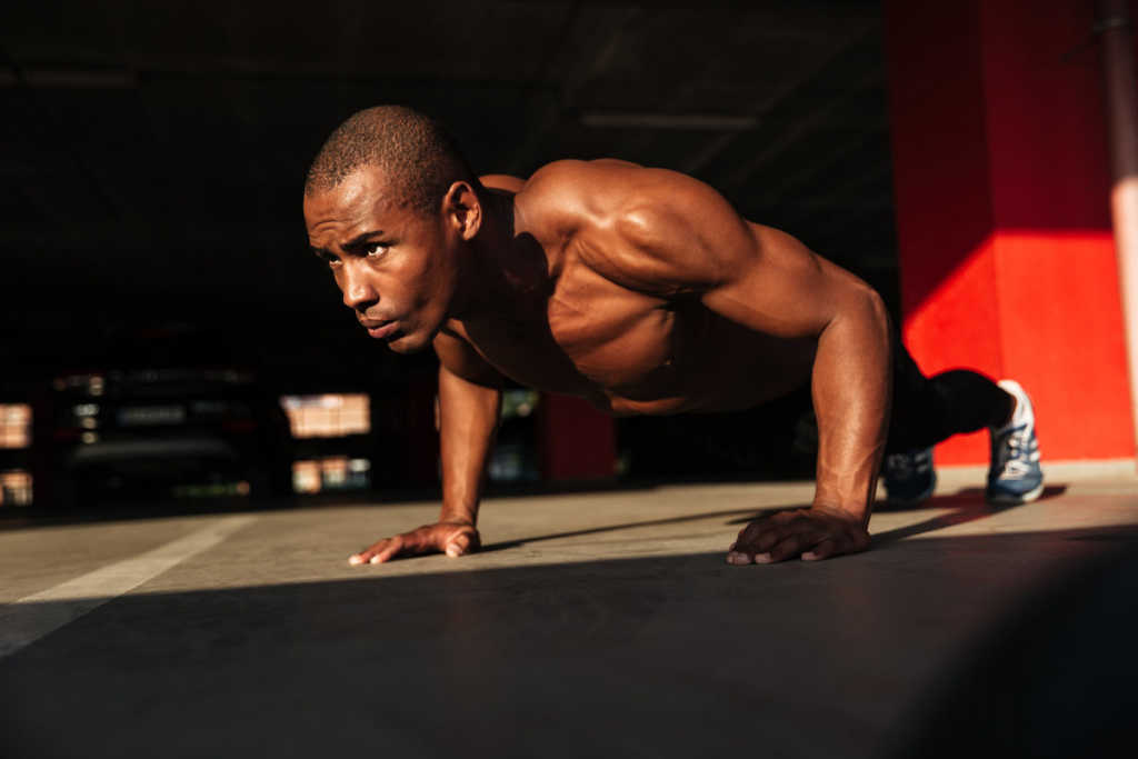 a half naked healthy african sportsman doing push ups indoors