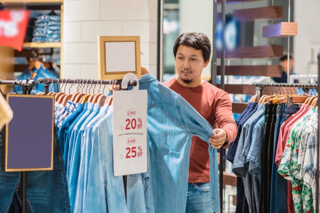 Smart Man With Beard Choosing Clothes In Clothing Store At Shopping Center